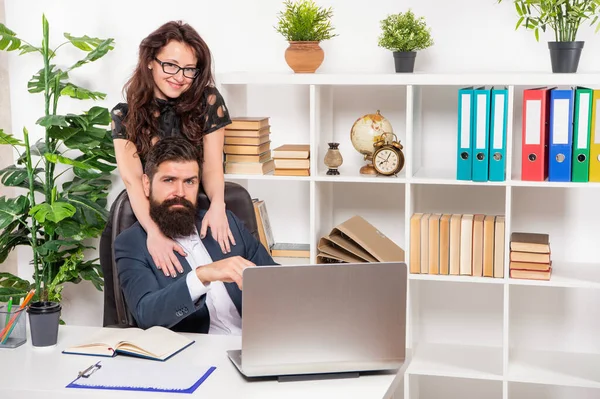 Mutlu kız, iş yerinde dizüstü bilgisayarda çalışan adamı kucaklıyor. — Stok fotoğraf