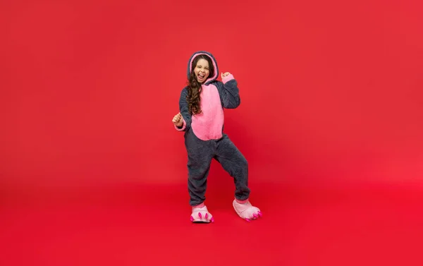 Blij kind in comfortabele pyjama op rode achtergrond, volledige lengte, pyjama — Stockfoto