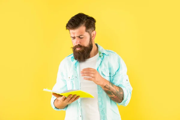 Chico hipster concentrado leyendo cuaderno sobre fondo amarillo, lector —  Fotos de Stock