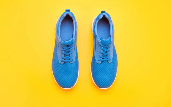 Sporty blue sneakers pair on yellow background, footwear — Stock Photo, Image