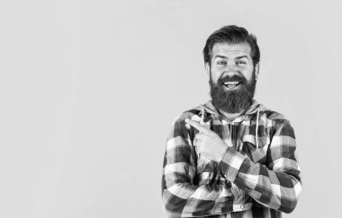 Ekose gömlekli olgun sakallı adam işaret ediyor. Sarı arka planda kareli gömlek giyen yakışıklı bir adam. Erkek güzellik ve moda. Dama gömlekli, kendinden emin ve katı bir adam. Boşluğu kopyala