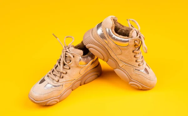 Elegantes zapatillas deportivas sobre fondo amarillo, calzado — Foto de Stock