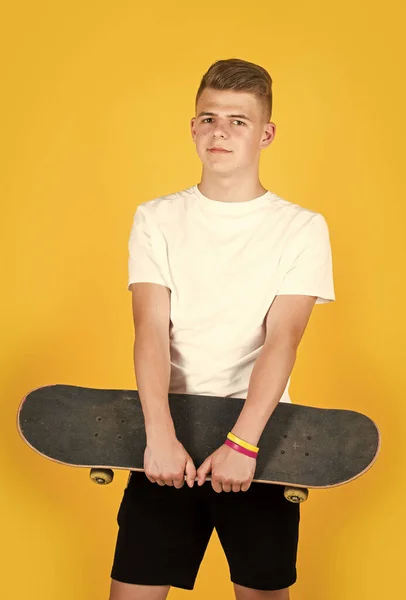 Teen chlapec nosit bílou ležérní tričko držet brusle palubě, hipster — Stock fotografie