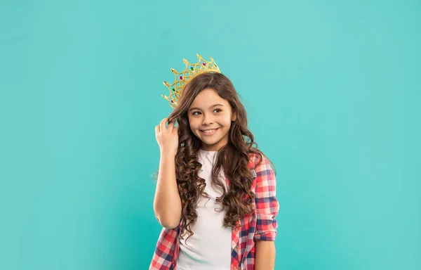 Fröhliches Kind mit lockigem Haar in Königinnenkrone auf blauem Hintergrund, Schönheit — Stockfoto