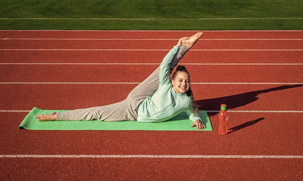 Kız çocuk spor antrenmanı stadyumun dışında yoga minderinde ve sağlık hizmetlerinde bölündü. — Stok fotoğraf