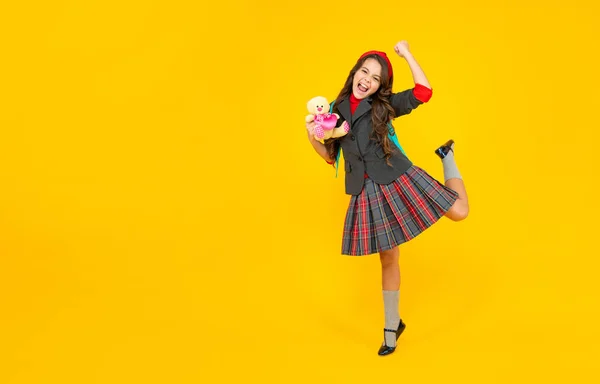 Blij kind in school uniform met speelgoed op gele achtergrond, september — Stockfoto