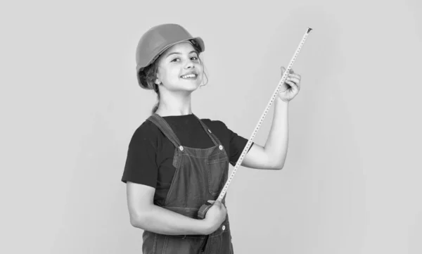 Подросток строитель в защитном шлеме использовать рулетку мера, измерение — стоковое фото