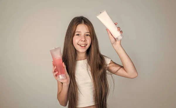 Cute child girl has trendy hairstyle and use lotion in bottle or scrub, beauty blog — Stock Photo, Image