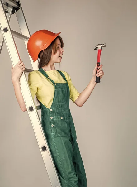 建設現場のハード帽子の女の子ははしごとハンマー、機械工を使用して — ストック写真