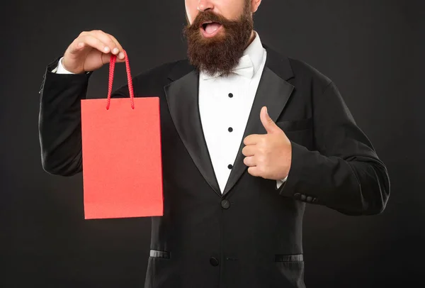 Hombre sorprendido en esmoquin corbata de lazo con compra bolsa de compras. espacio de copia. Pulgar hacia arriba. — Foto de Stock