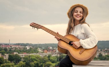 Moda görünümlü kız akustik gitar ve müzik çalıyor.