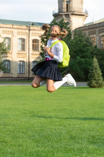 Gelukkig energiek meisje in uniform met schooltas springen voor vreugde, terug naar school — Stockfoto