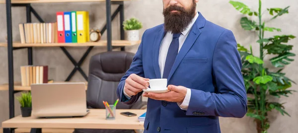 Обрезанный жестокий генеральный директор в деловом костюме провести утреннюю чашку кофе в офисе, обеденный перерыв — стоковое фото