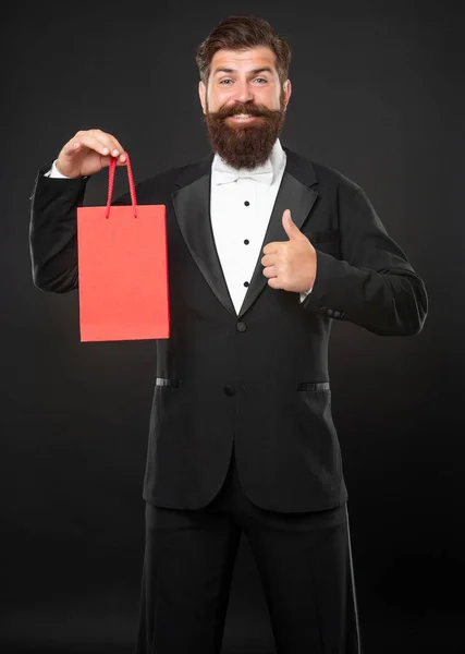 Happy man in tuxedo bow tie with shopping bag for mens day. copy space. thumb up. — Stock Photo, Image