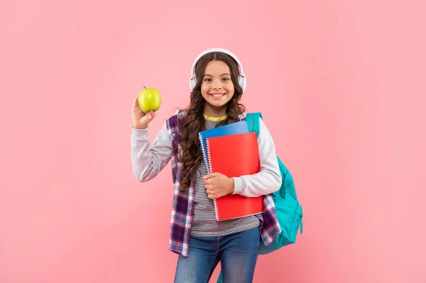 Wesoła nastolatka w słuchawkach z jabłkiem. Słuchaj muzyki. nowa technologia. — Zdjęcie stockowe