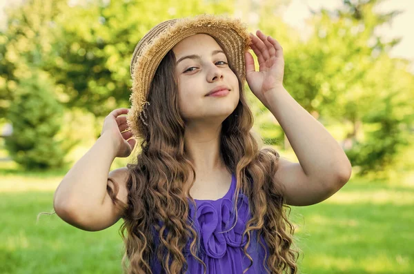 Niña pequeña con cabello ondulado largo y aspecto de belleza fijar sombrero de sol de moda en el paisaje soleado de verano, fashionista — Foto de Stock