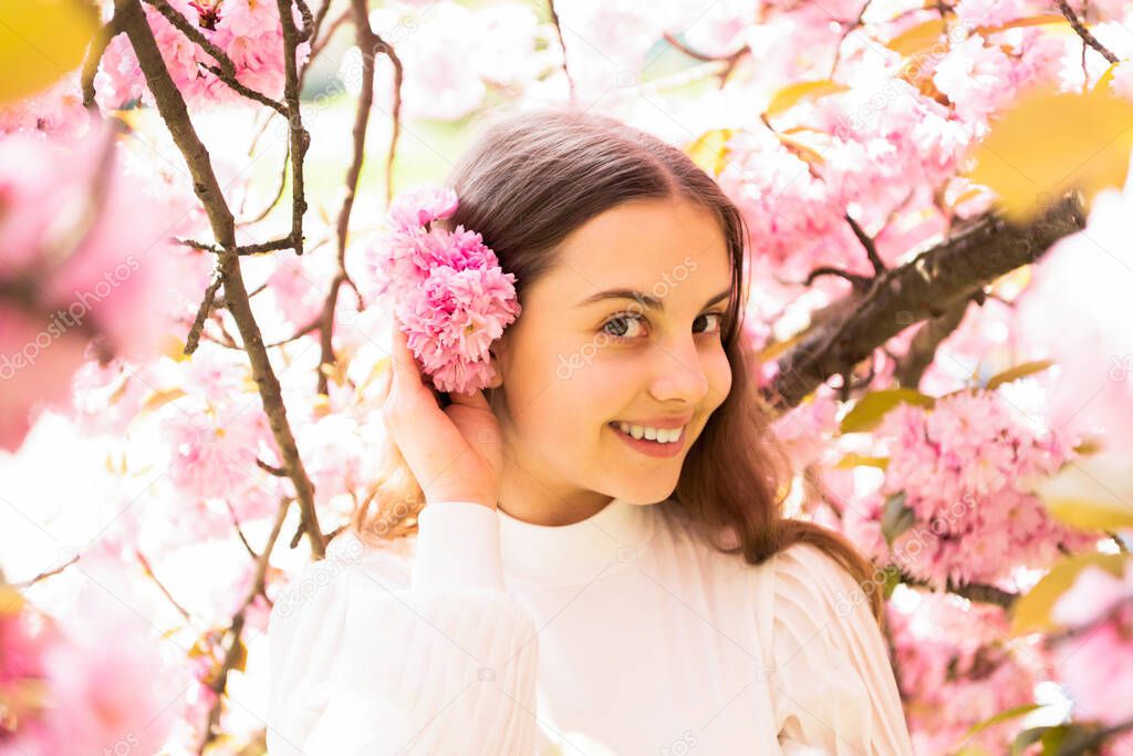 positive teen girl at sakura flower bloom in spring