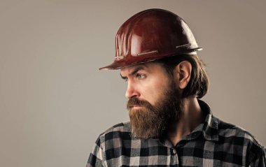 Kareli gömlekli sakallı erkek hippi ve işçi kaskı, alet edevat dükkanı.