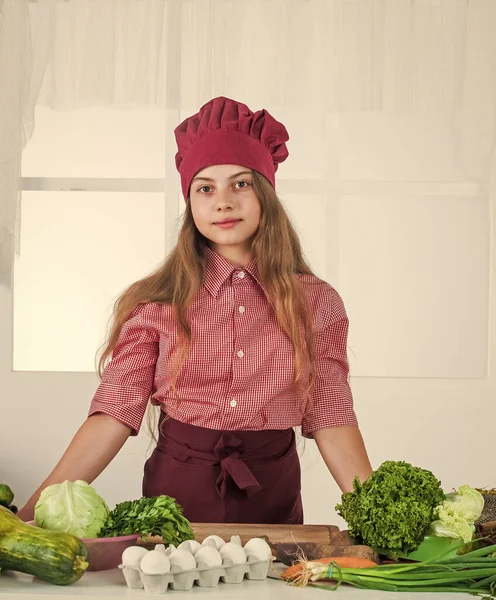 Leende tonåring flicka i kock uniform matlagning grönsaker, vegetarian — Stockfoto