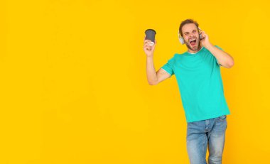 Kulaklıklı genç adam kahve içer. Müzik aşığı. Müzik dinle. kablosuz aygıt aksesuarı.