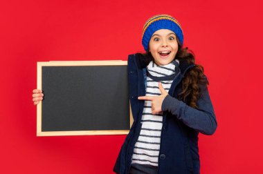 Şaşkın çocuk şapkalı tahtayı işaret ediyor. Kopya alanı olan karatahta tutan genç kız.