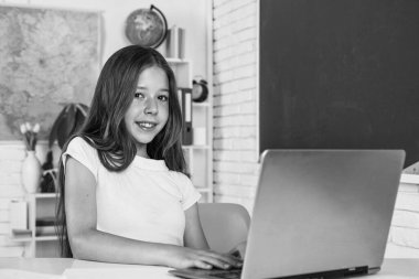 Modern eğitim. Bilgi günü. Çocuk öğrenci masaya otur ve bilgisayar kullan. Kız üniversite öğrencisi. Okula dönüyorum. Genç kız sınıfta dizüstü bilgisayarla çalışıyor. Neşeli çocuk çevrimiçi konu öğreniyor