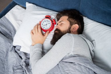 Yatakta çalar saatle uyuyan adam, uyku zamanı.