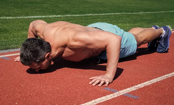 Atletische gespierde man doet push-ups outdoor op het stadion, macht — Stockfoto