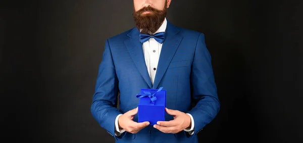 Hombre recortado en esmoquin corbata formalwear sobre fondo negro con caja de regalo. día de boxeo — Foto de Stock