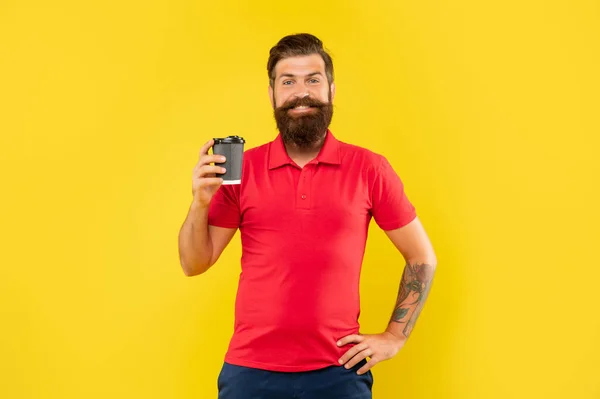Happy guy in casual red tshirt holding jednorazowy kubek żółty tło, papier filiżanka kawy — Zdjęcie stockowe