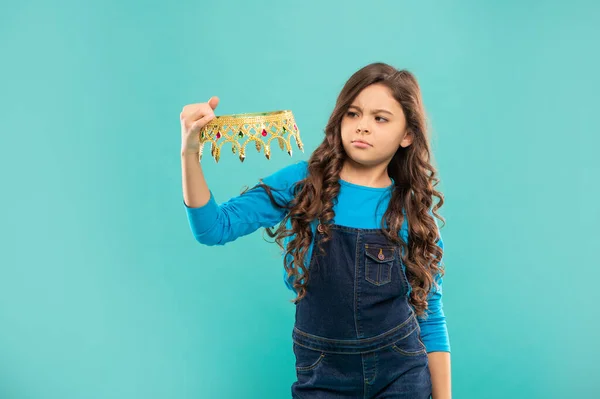 Σοβαρή έφηβος κορίτσι με σγουρά μαλλιά κρατήσει στέμμα σε μπλε φόντο, εγωιστής — Φωτογραφία Αρχείου