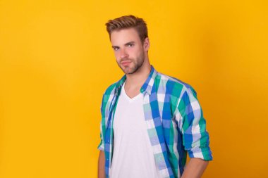 Yakışıklı görünüşüm benim malım. Yakışıklı bir erkek portresi. Genç adam sarı arka plan