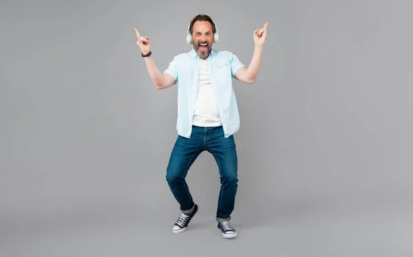 Fröhliche Altrocker singen Rockmusik mit Kopfhörern und machen Hupsignale grauen Hintergrund, Song — Stockfoto