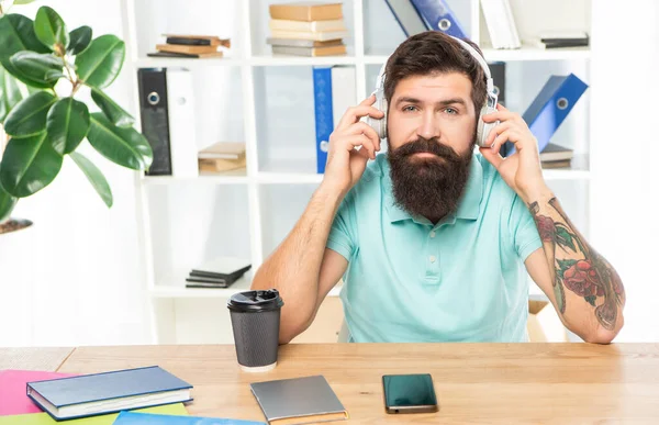Hombre de negocios serio escuchando melodía en auriculares en la oficina, música —  Fotos de Stock