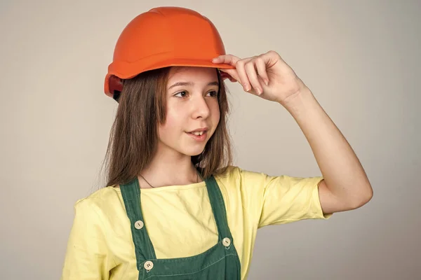 Tonårstjej i hjälm och panndräkt. Barnet bär hatt. Grabbbyggare på byggarbetsplatsen. Arbetaringenjör. Arkitekt i verkstad. Renovering och reparation. Självsäker mekaniker — Stockfoto