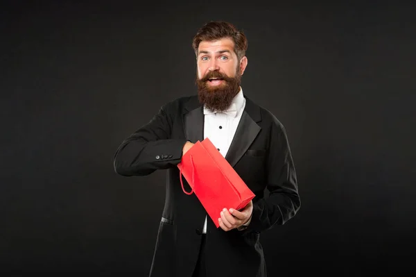 Homem surpreso em smoking arco gravata formalwear no fundo preto com saco de compras. aniversário — Fotografia de Stock