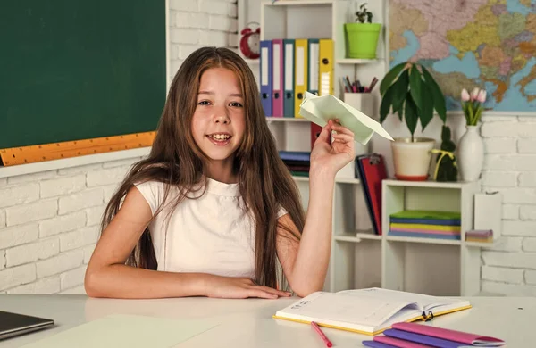 Veselé dítě dívka drží papírové letadlo ve škole lekce, škola — Stock fotografie