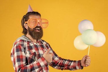 Kareli tişörtlü, parti balonlu, doğum günü olan olgun ve yakışıklı bir adam.