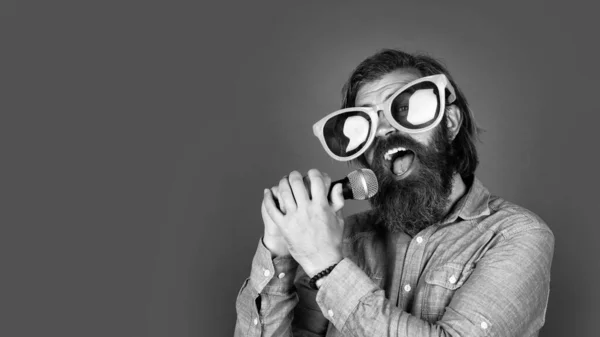 Lustiger bärtiger brutaler Mann mit Schnurrbart trägt Partybrille und singt Song in Mikrofon, Karaoke — Stockfoto