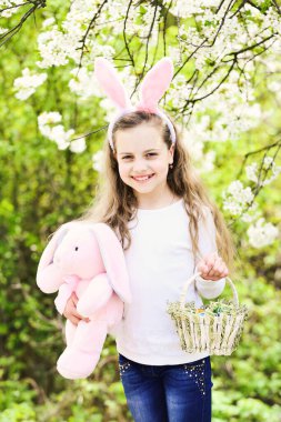 Arka planda çiçek ağacı, Paskalya pozu veren sepetli çocuk