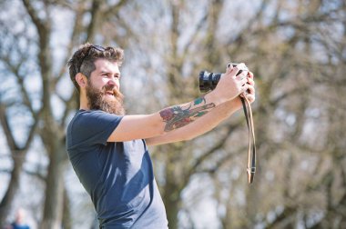 Sakallı adam selfie vintage kameraya alıyor. Sakal ve bıyık neşeli yüzündeki defocused arka plan, dallarda olan adam. Selfie alarak meşgul uzun sakallı adam. Fotoğrafçı kavramı