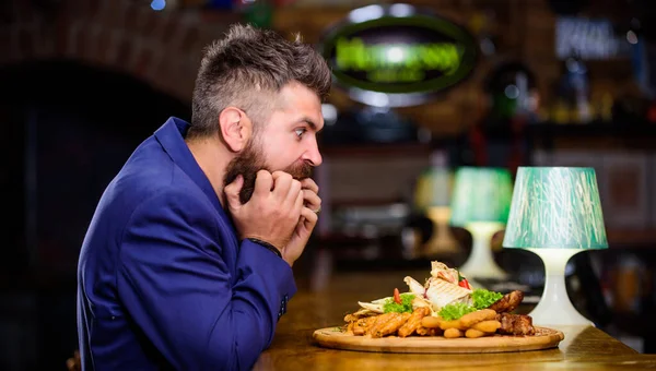 Man received meal with fried potato fish sticks meat. Enjoy meal. High calorie snack. Cheat meal concept. Hipster hungry eat pub fried food. Manager formal suit sit at bar counter. Delicious meal