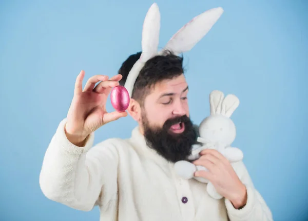 Kijk eens naar dat ei. Baard man met konijnenspeelgoed en paaseieren. Paashaas levert gekleurde eieren. Viering van de voorjaarsvakantie. Hipster met lange konijnenoren met ei leggende haas — Stockfoto