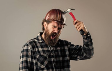 Çekiçli üniformalı erkek işçi. Çalışan aletleri olan bir inşaatçı. Acımasız olgun hippi.