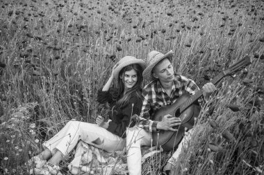 Kırmızı çiçekli bir tarlada gitar çalan romantik çift, yaz tatili.