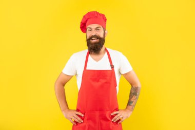 Kırmızı ceketli ve önlüklü, sarı kollu mutlu bir adam, şef.