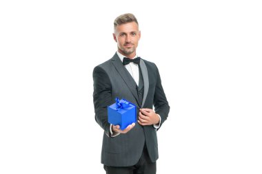 Smokinli ve papyonlu neşeli adam beyaz arka planda izole edilmiş hediye kutusunu tutuyor.