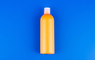 mavi arka planda turuncu şampuan şişesi, tuvalet malzemeleri