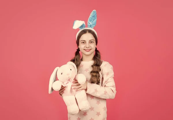 Щаслива великодня дівчина-підліток у кролячих вухах і піжамах грати з іграшкою, Великдень — стокове фото