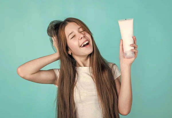 Veselá dívka kondice vlasy s rovnátka. dospívající dítě čištění vlasů s šamponem. kluk prezentující sprchový gel. kosmetika pro péči o tělo. pleťové mléko nebo drhnutí. silný a odolný. Dřív vypadala perfektně. — Stock fotografie